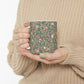 A white ceramic mug with a pink floral and pomegranate design inspired by William Morris.