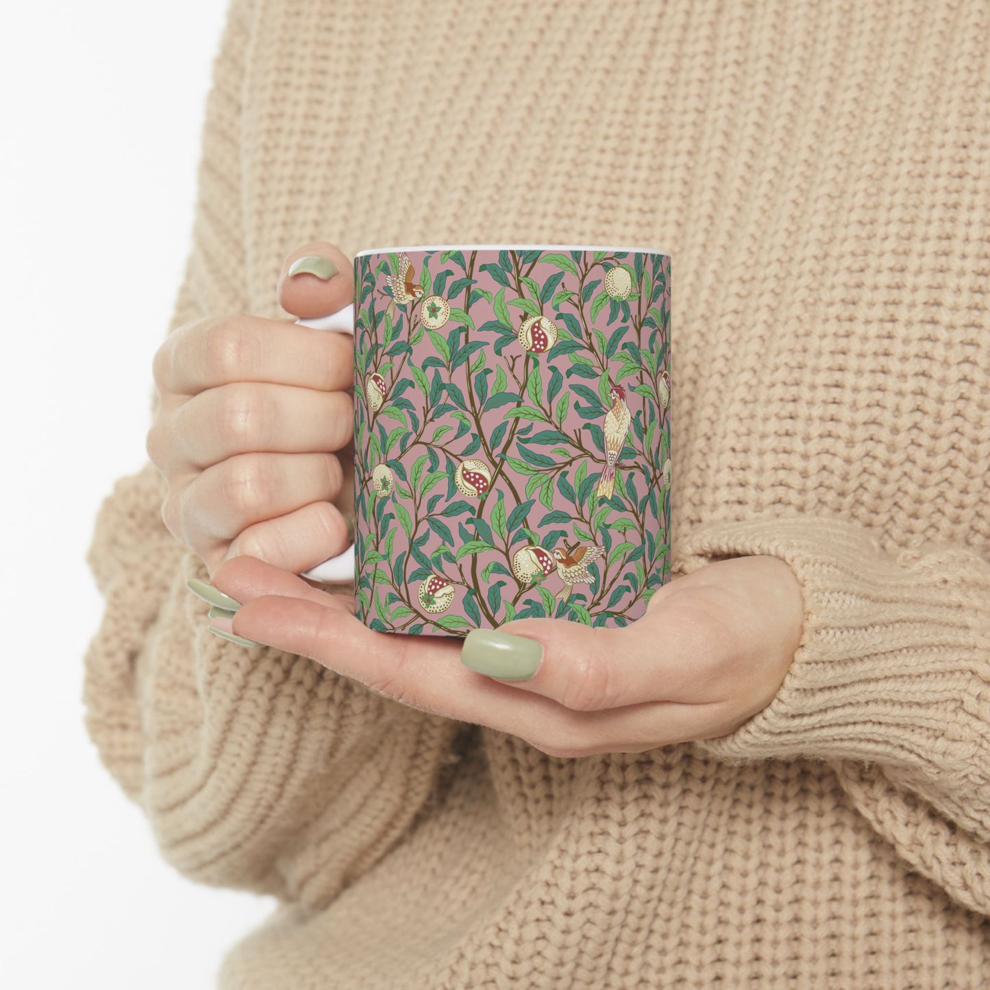 A white ceramic mug with a pink floral and pomegranate design inspired by William Morris.