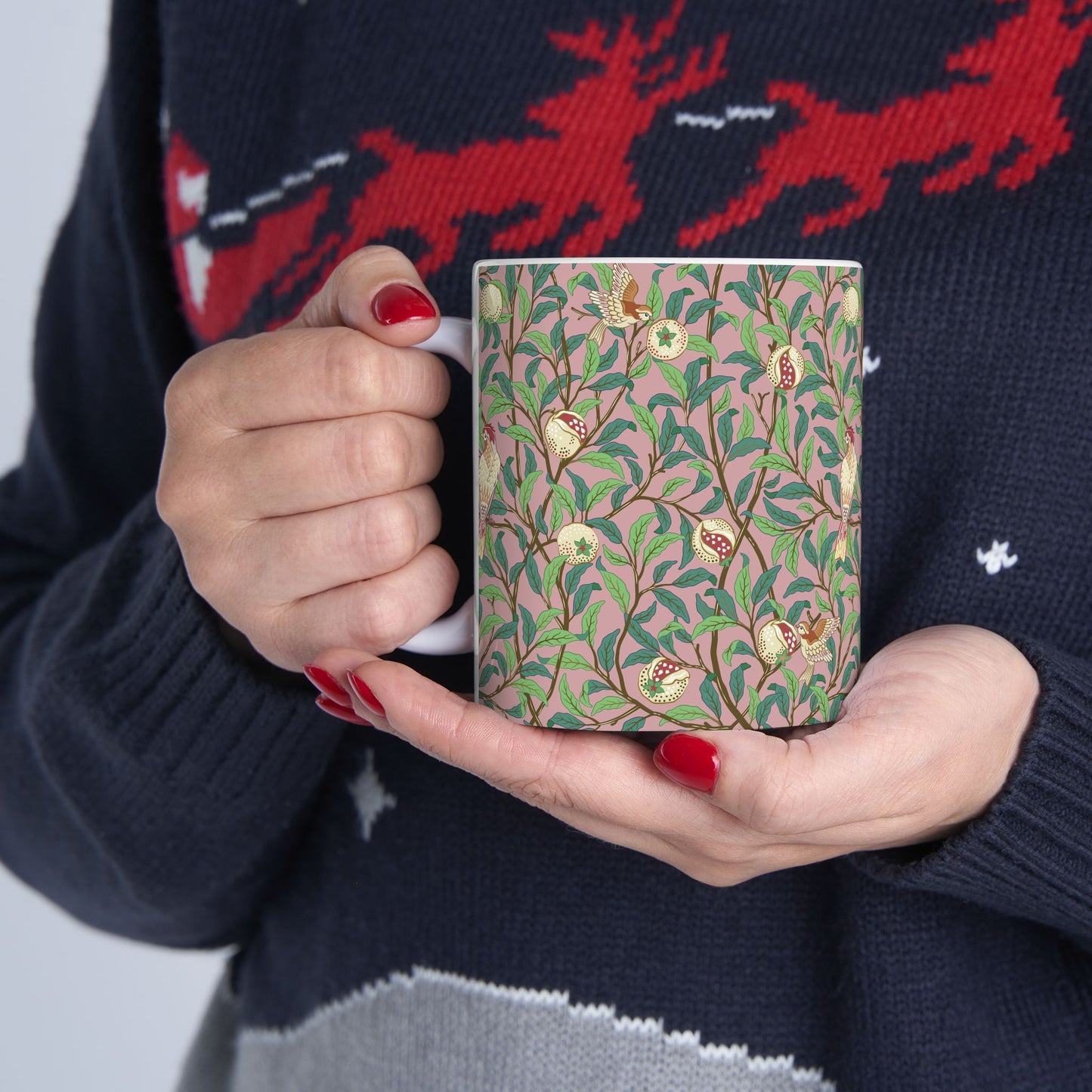 A white ceramic mug with a pink floral and pomegranate design inspired by William Morris.