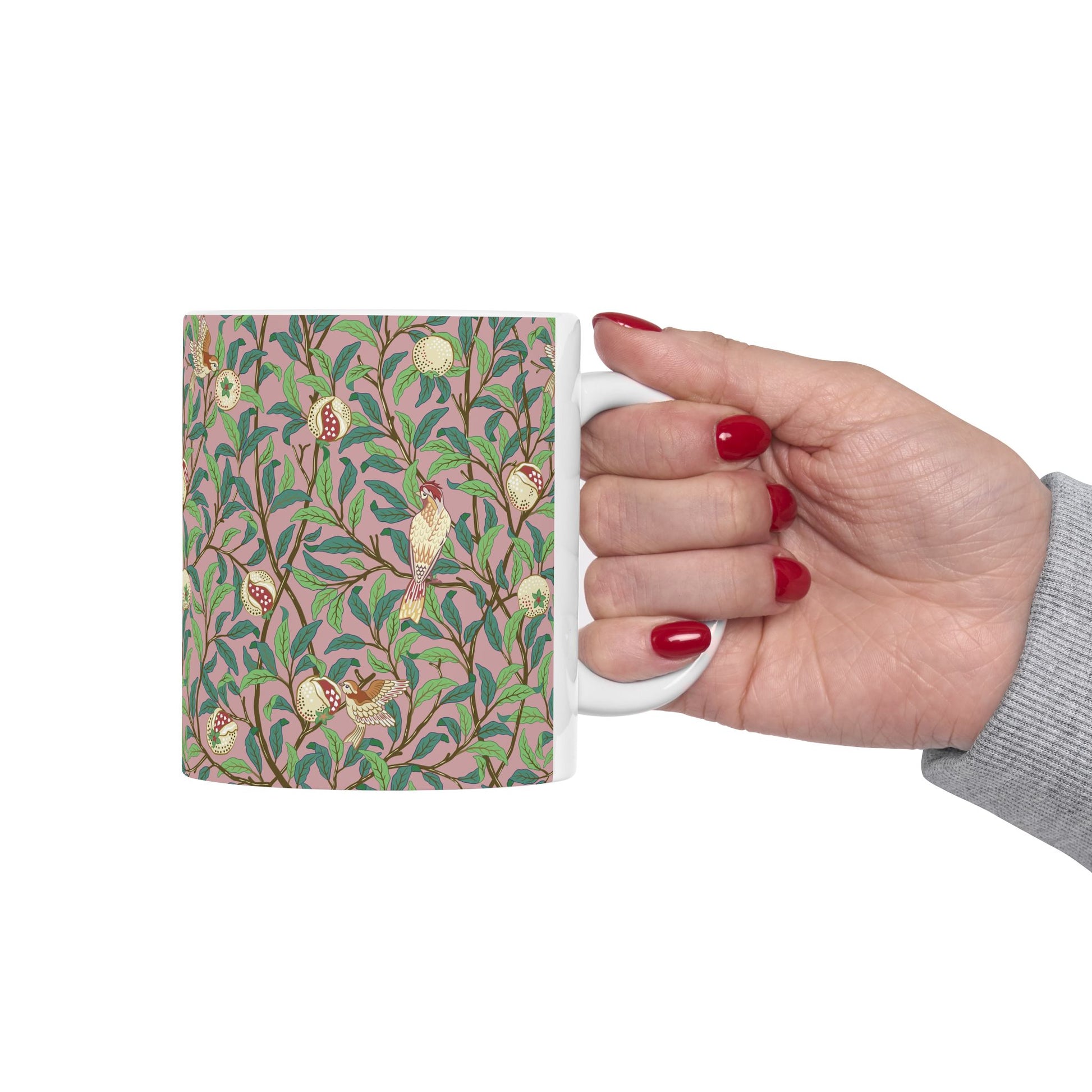 A white ceramic mug with a pink floral and pomegranate design inspired by William Morris.