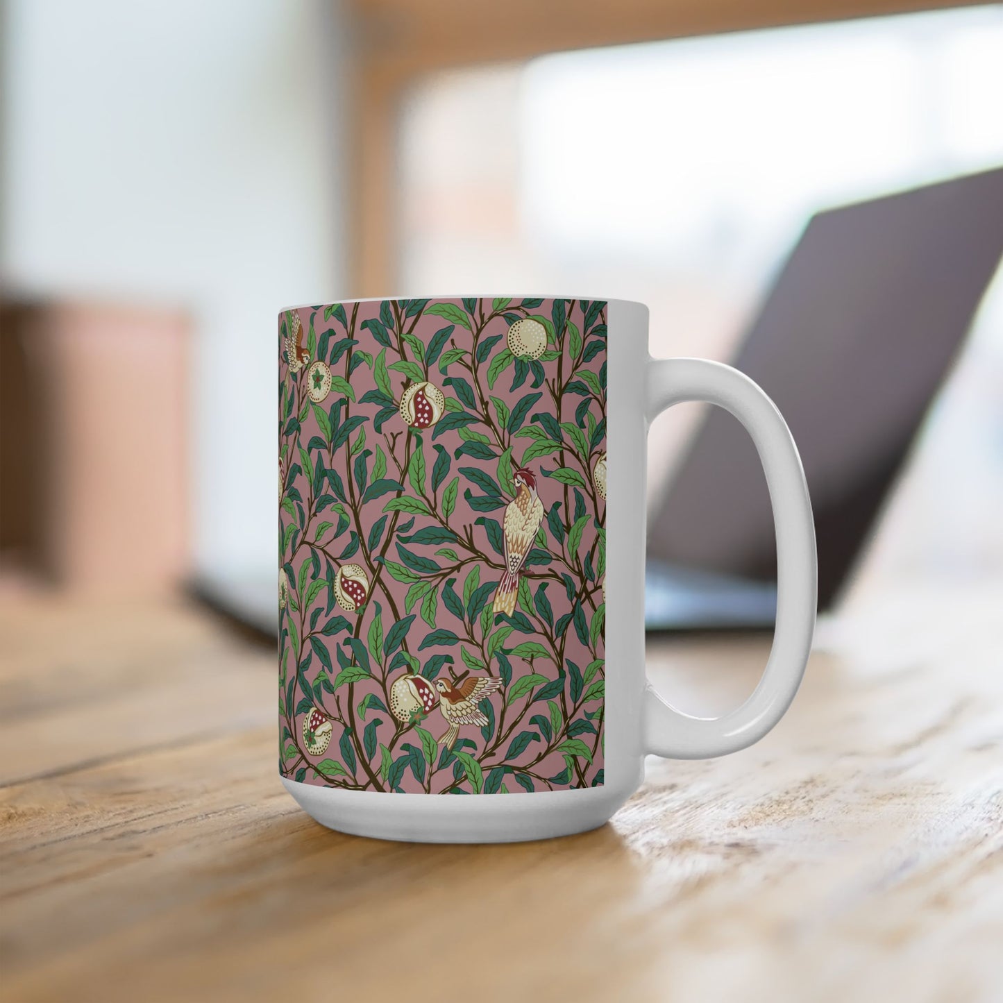 A white ceramic mug with a pink floral and pomegranate design inspired by William Morris.