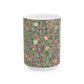 A white ceramic mug with a pink floral and pomegranate design inspired by William Morris.