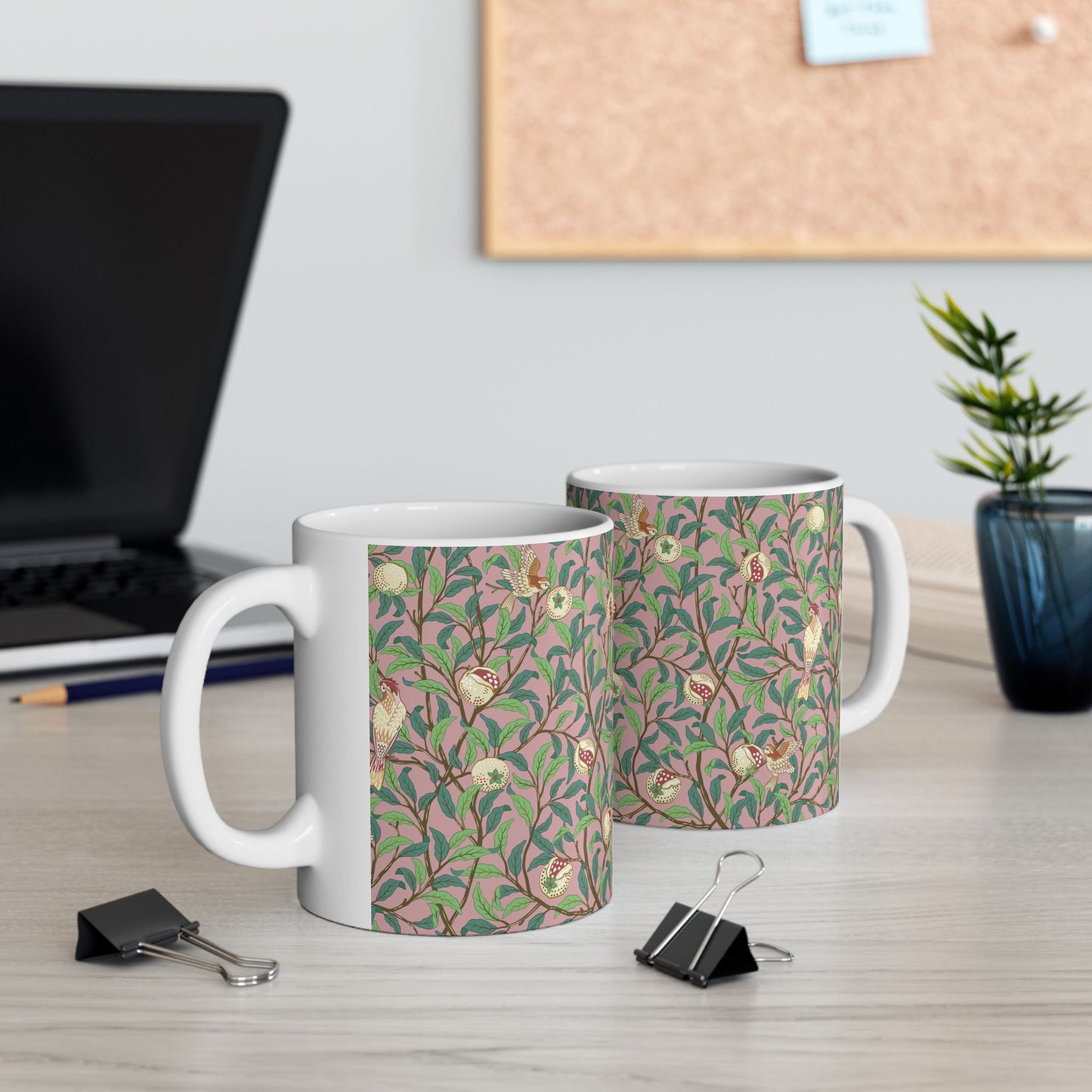 A white ceramic mug with a pink floral and pomegranate design inspired by William Morris.