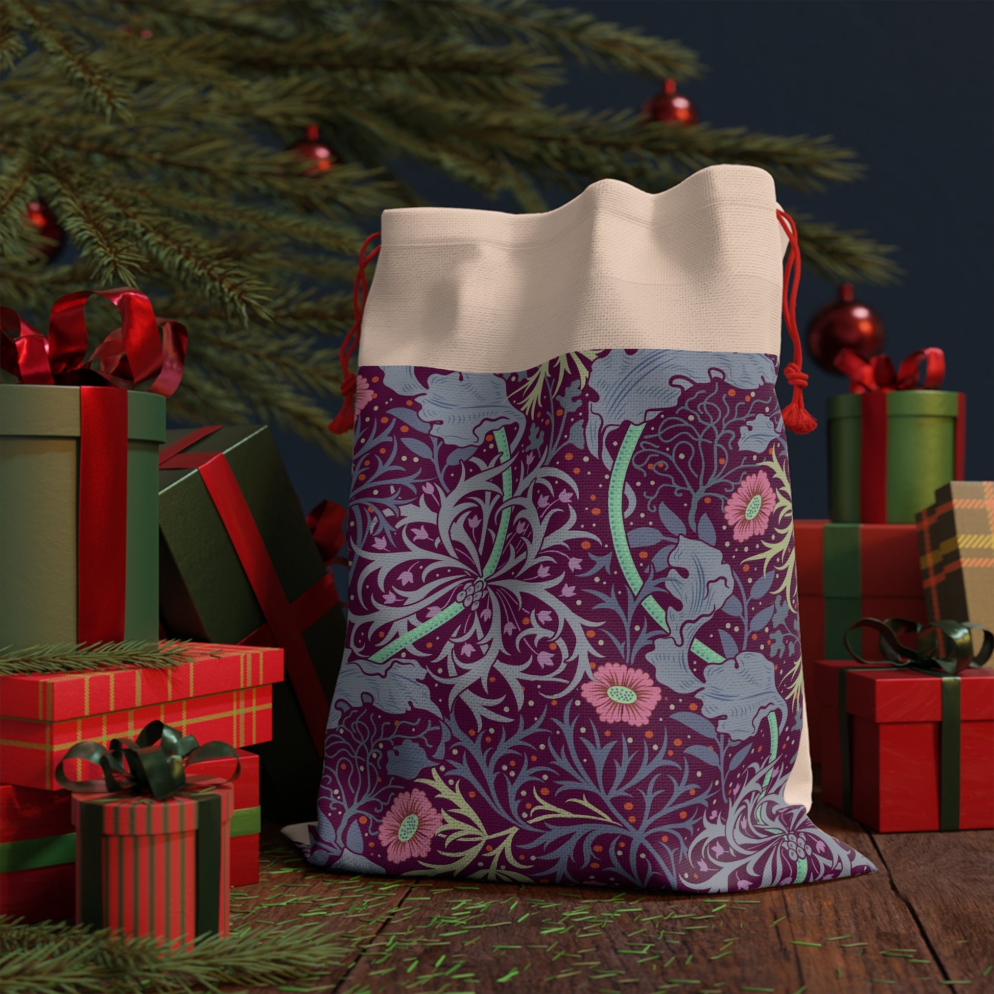 A rectangular Christmas-themed linen drawstring bag with a floral William Morris & Co pattern in pink and green on a beige background, and a red drawstring at the top.