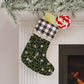 A Christmas stocking with a floral and bird design, featuring a black and white plaid pattern at the top and a wood loop for hanging.