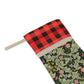 A one-sided printed Christmas stocking with a floral design, featuring a red and black plaid top cuff and a green body.