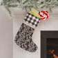 A Christmas stocking with a floral pattern in a red and black or white and black checkered design, featuring a wooden hanging loop.