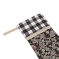 A Christmas stocking with a floral pattern in a red and black or white and black checkered design, featuring a wooden hanging loop.