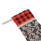 A Christmas stocking with a floral pattern in red, black, and white colours, featuring a plaid design on the top cuff.