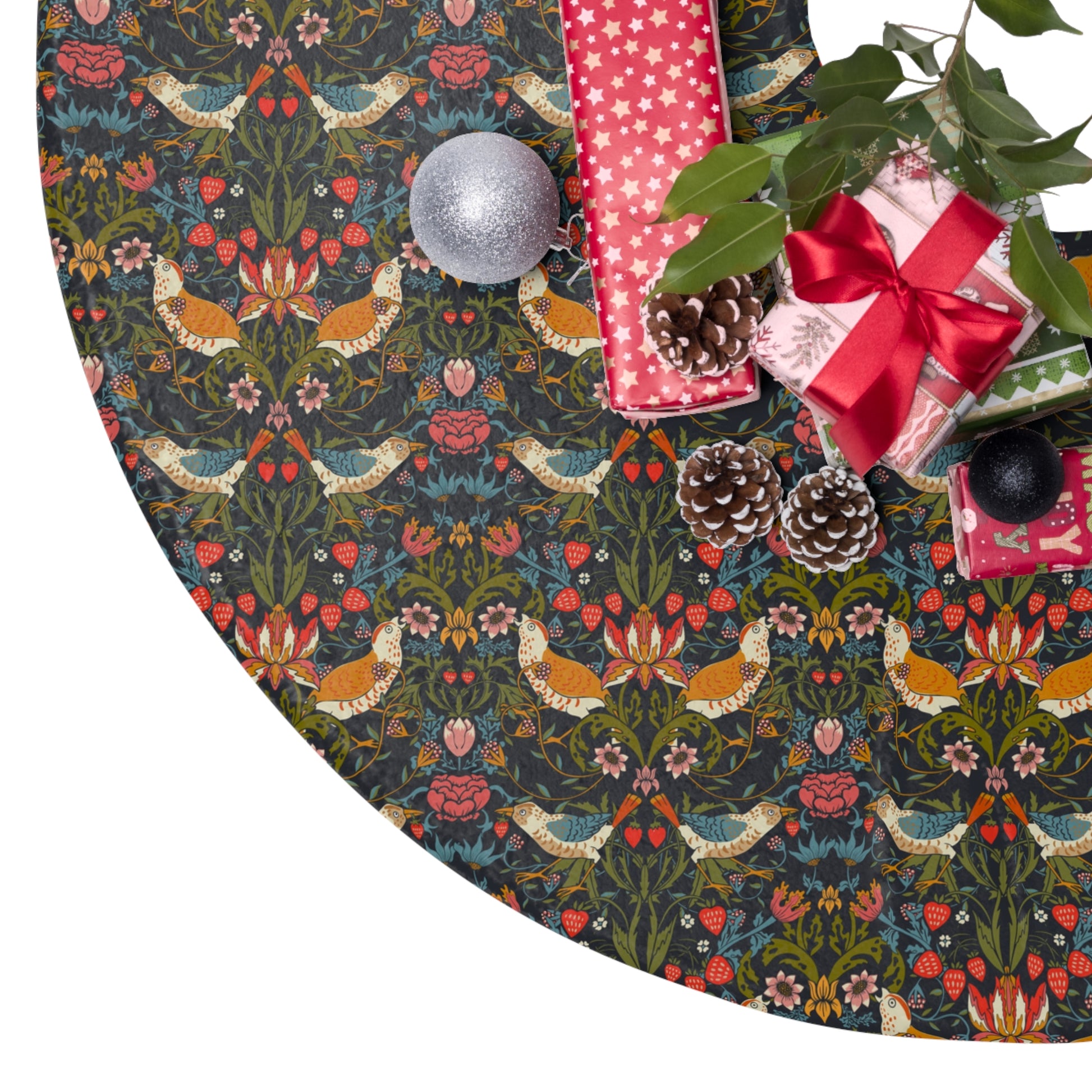 Decorative Christmas tree skirt with floral and bird pattern, surrounded by gift boxes and pinecones.