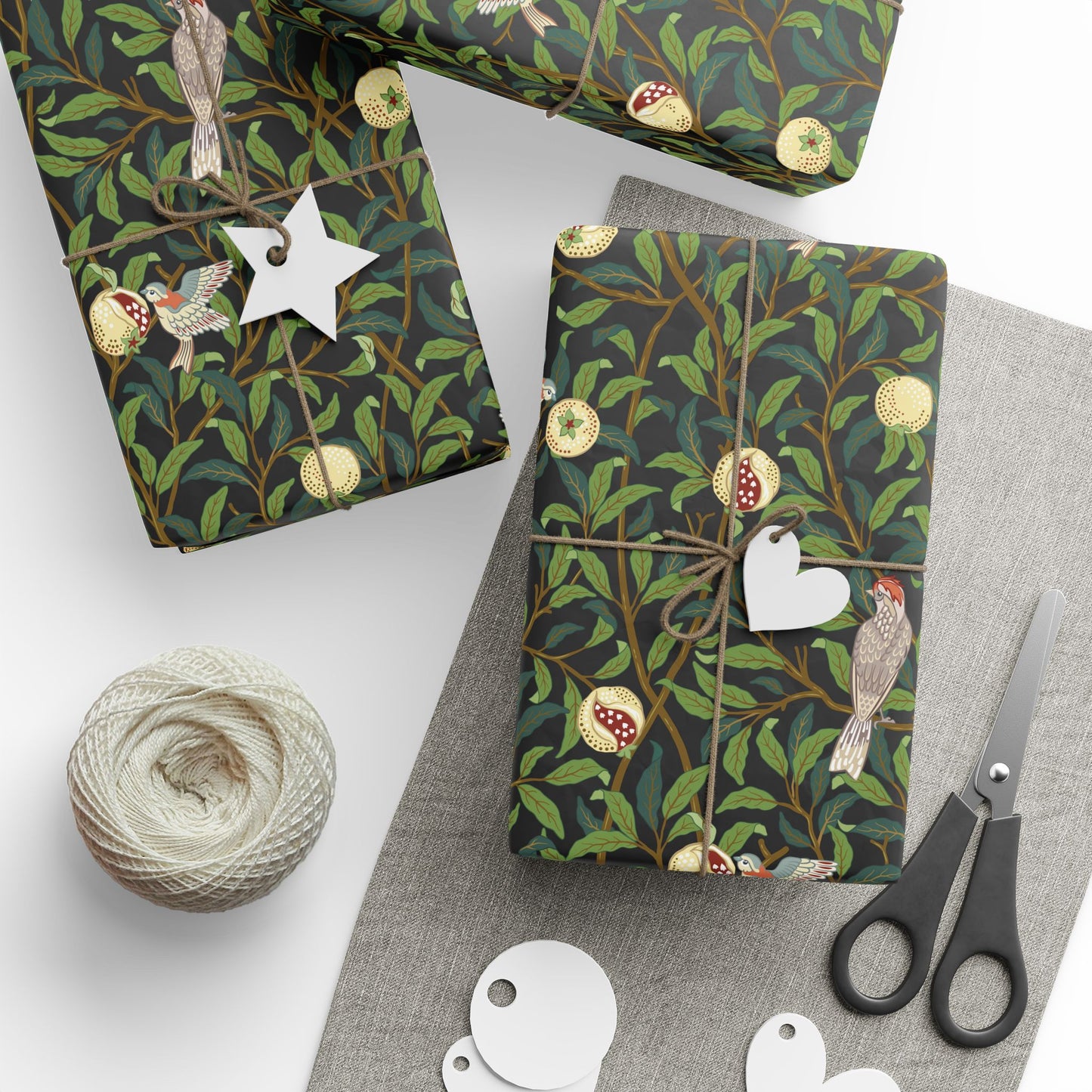 Gift boxes with nature-themed wrapping paper, scissors, and yarn on a white surface.