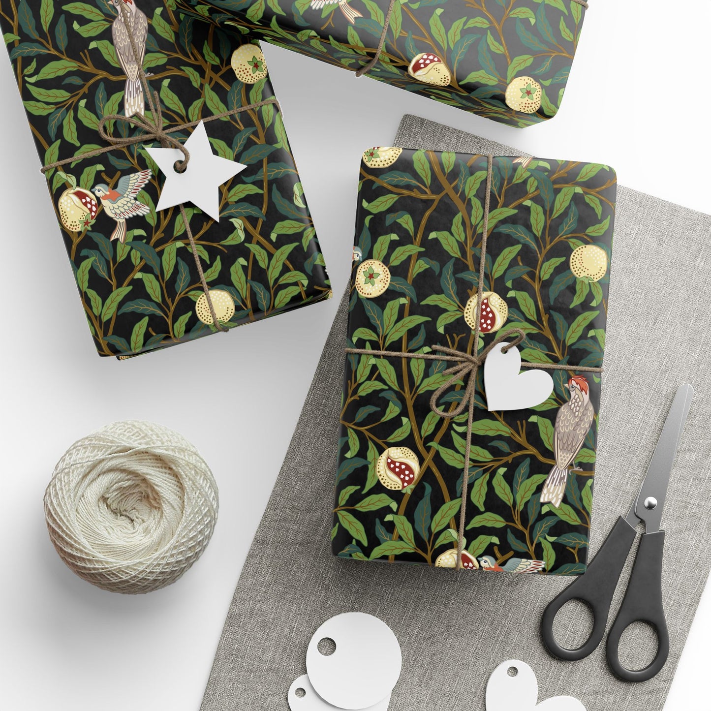 Gift boxes wrapped in decorative paper with birds and branches, surrounded by scissors and yarn.