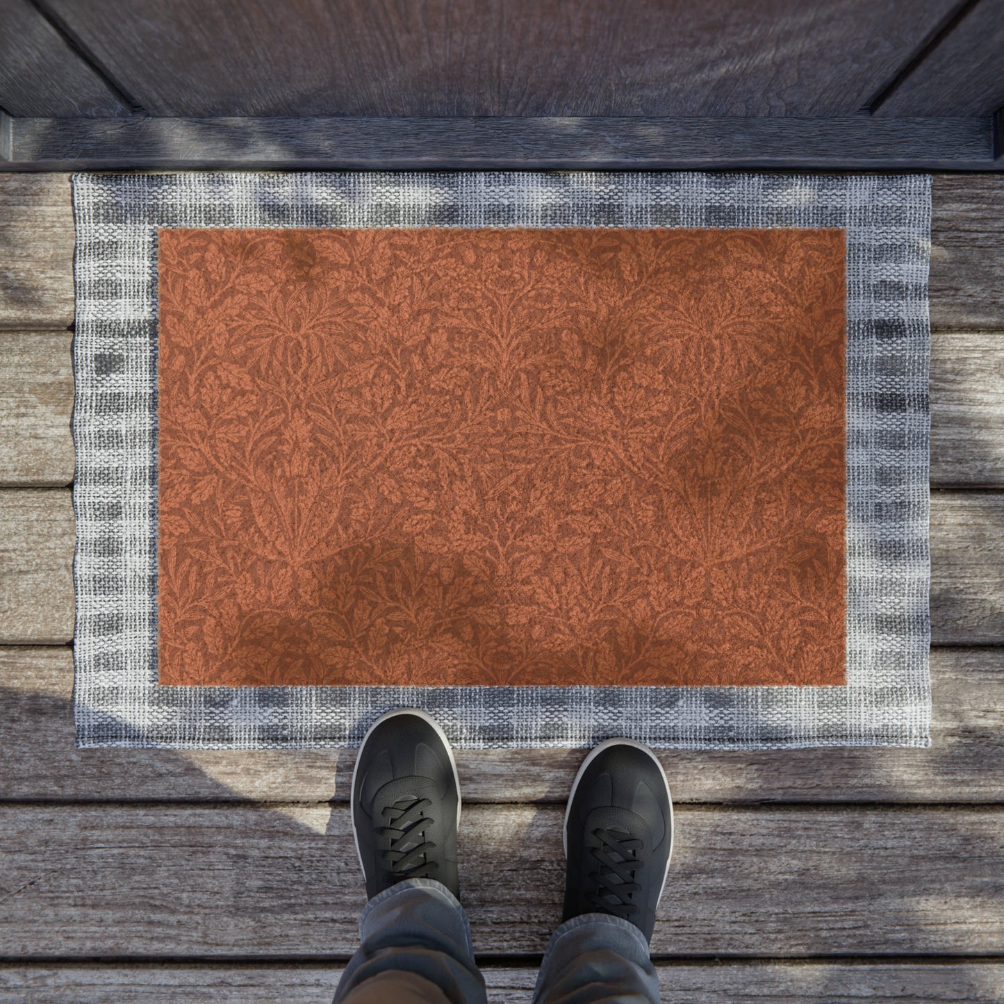 A rectangular coconut coir doormat with an intricate floral William Morris & Co pattern in a rust colour, mainly for outdoor use.
