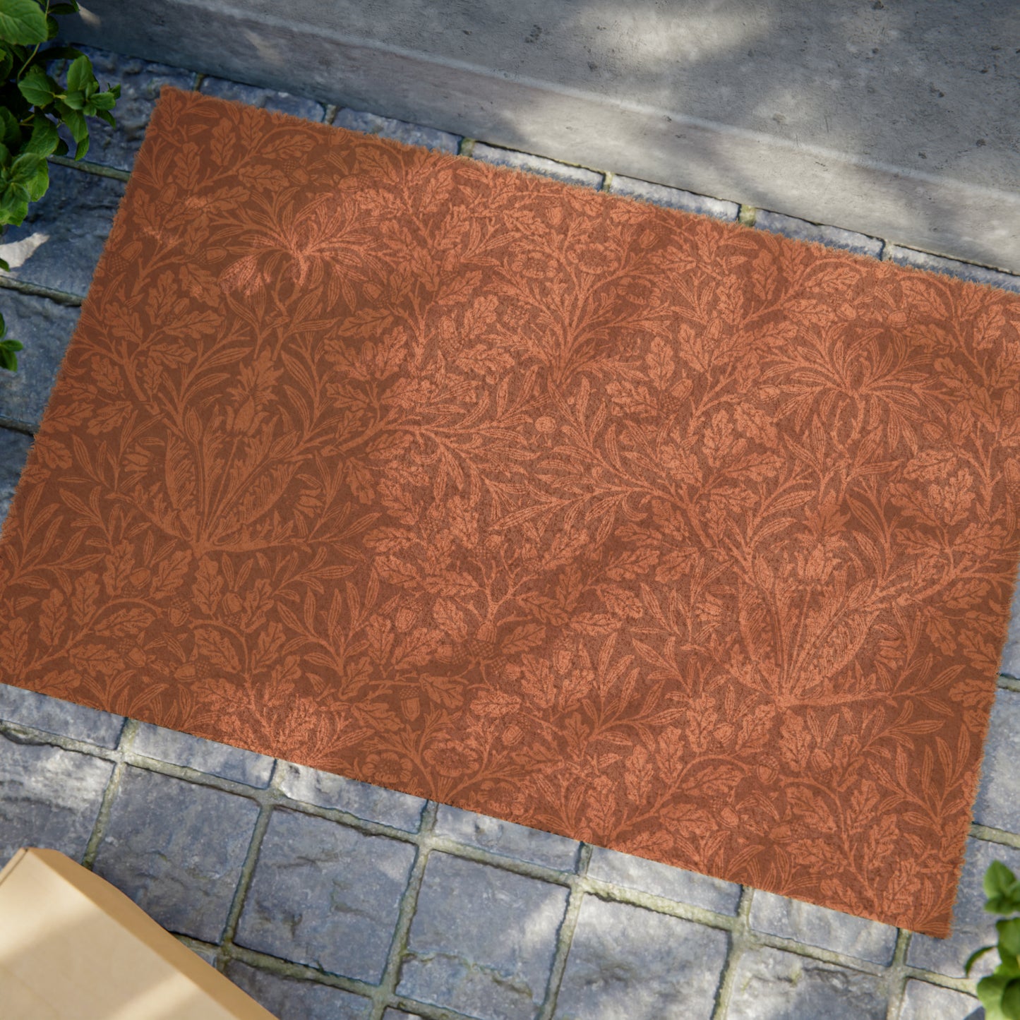 A rectangular coconut coir doormat with an intricate floral William Morris & Co pattern in a rust colour, mainly for outdoor use.