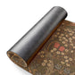 A rolled piece of dark gray textured material shown beside an unrolled section of a vintage-style floral rug with brown, beige, and muted red patterns on a white background.