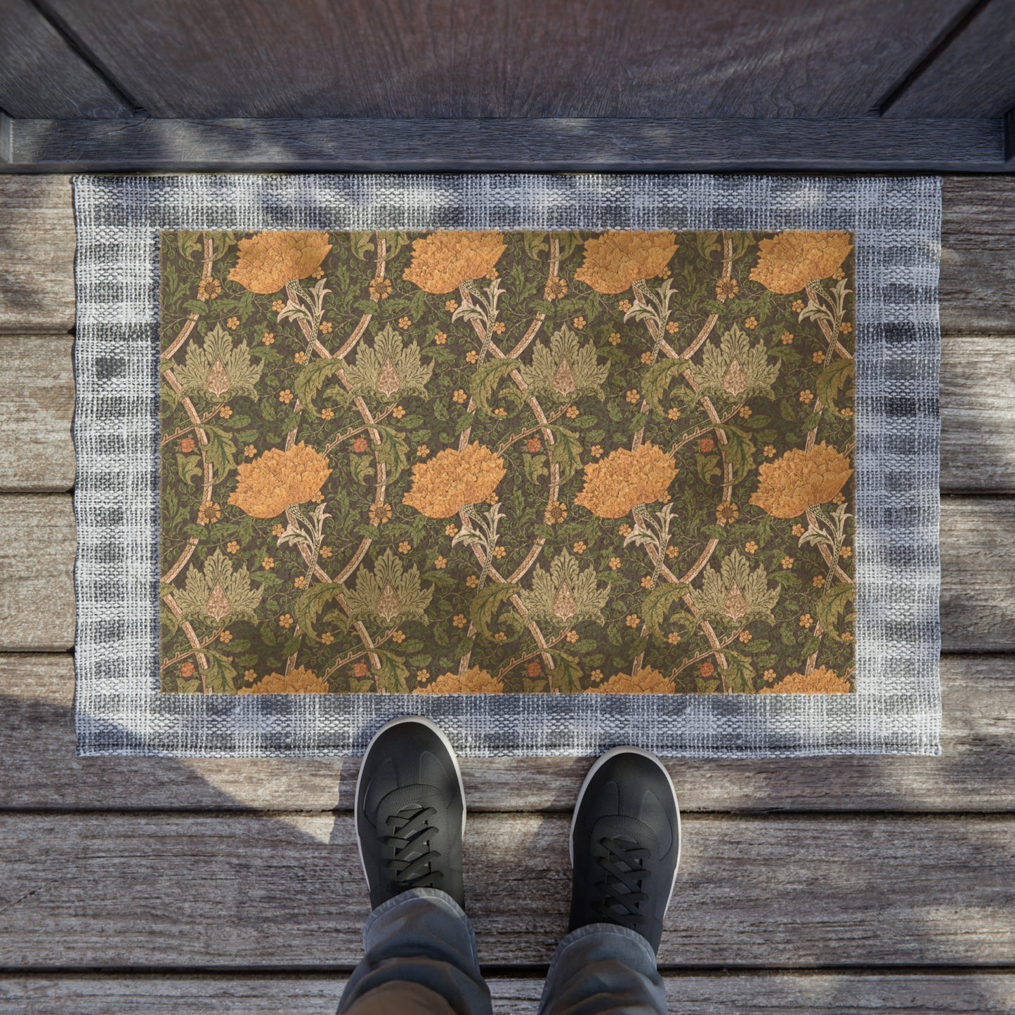 A rectangular coconut coir doormat with an intricate floral pattern inspired by William Morris, featuring a mix of green, brown, and yellow colours.