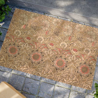 A rectangular area rug with an intricate floral and leaf pattern in shades of brown, beige, and muted red, laid out on a gray stone pavement.