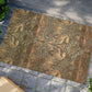 Decorative doormat with intricate patterns on a stone pavement