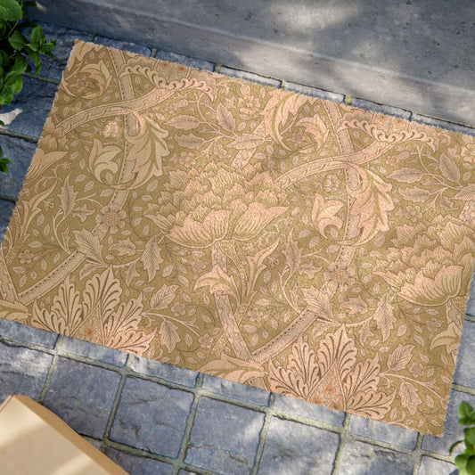 A rectangular area rug with an ornate floral and botanical damask pattern in warm tan and beige tones, shown laid out on gray stone pavers outdoors.