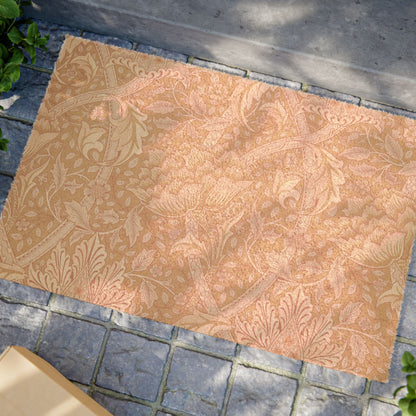 A rectangular area rug with an ornate floral and botanical damask pattern in warm peach, tan, and muted pink tones, shown laid out on a gray stone paver surface outdoors.