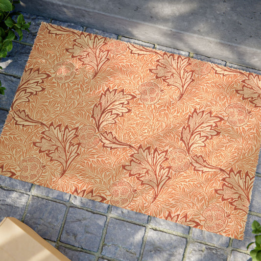 A rectangular area rug with a repeating botanical leaf pattern in terracotta red and beige, laid out on gray stone pavers outdoors.