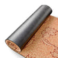 A rolled sheet of patterned wallpaper or fabric shown on a white background, with the outer roll in dark charcoal and the unrolled section displaying a warm orange and brown botanical pattern.