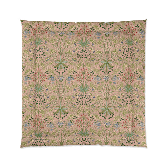 A comforter with a floral William Morris & Co pattern primarily in pink and green shades, featuring a geometric double square quilting design.