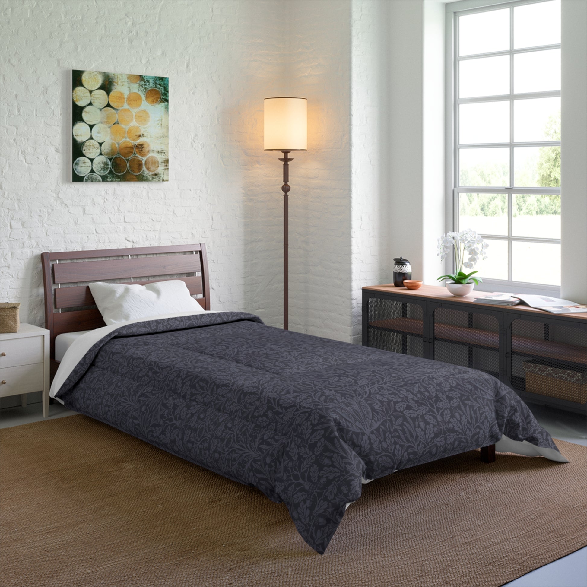 A smoky blue comforter with a geometric William Morris & Co pattern of acorns and oak leaves on a white background, displayed on a flat surface.