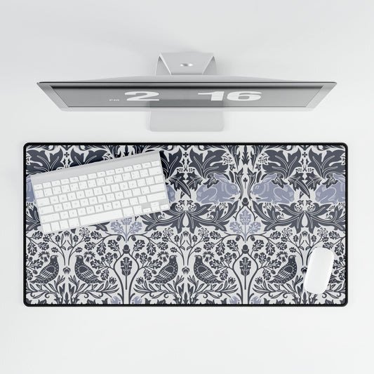 Desk setup with a decorative desk mat featuring a floral and bird pattern, keyboard, and computer monitor.