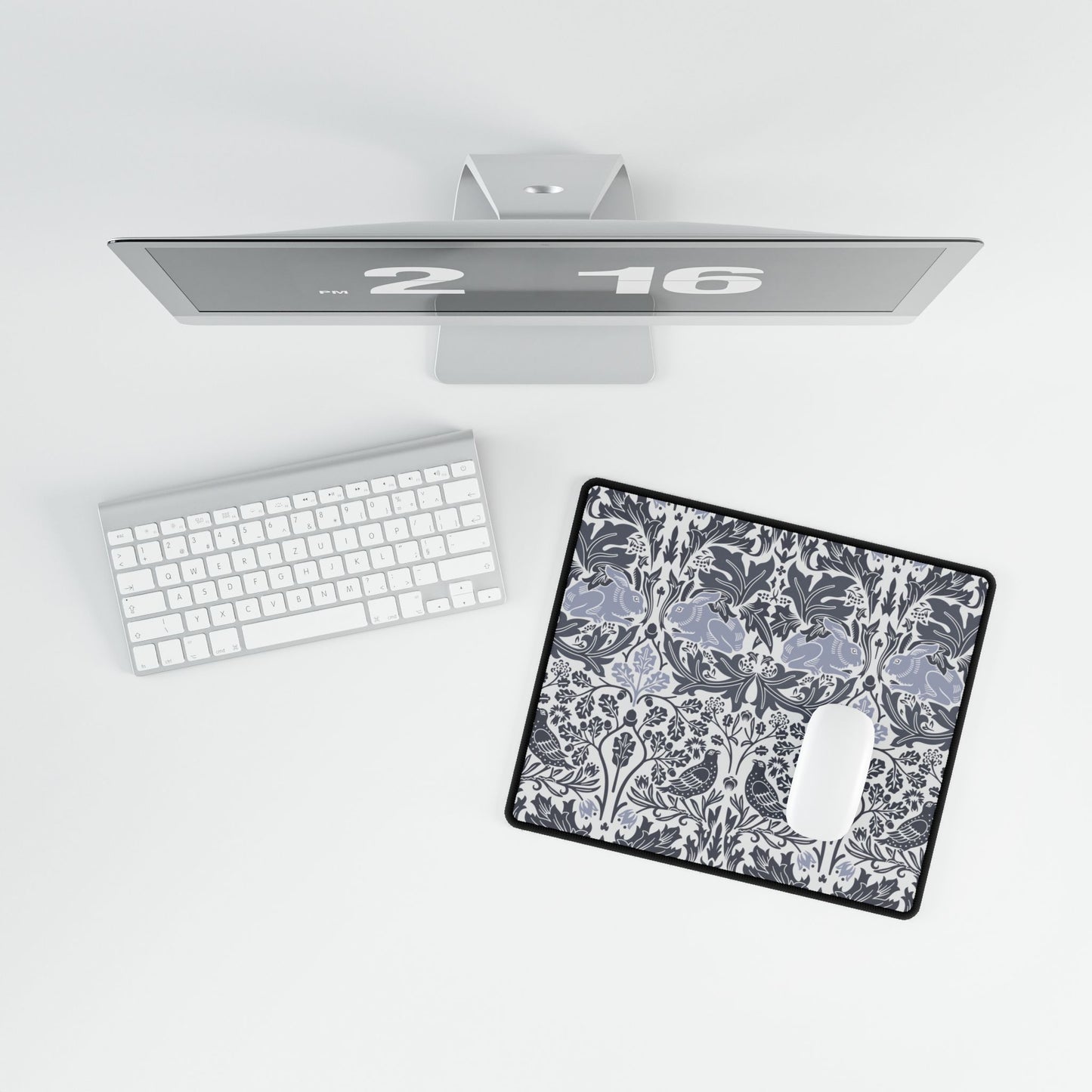 Computer monitor, keyboard, and mouse on a desk with a decorative mouse pad.