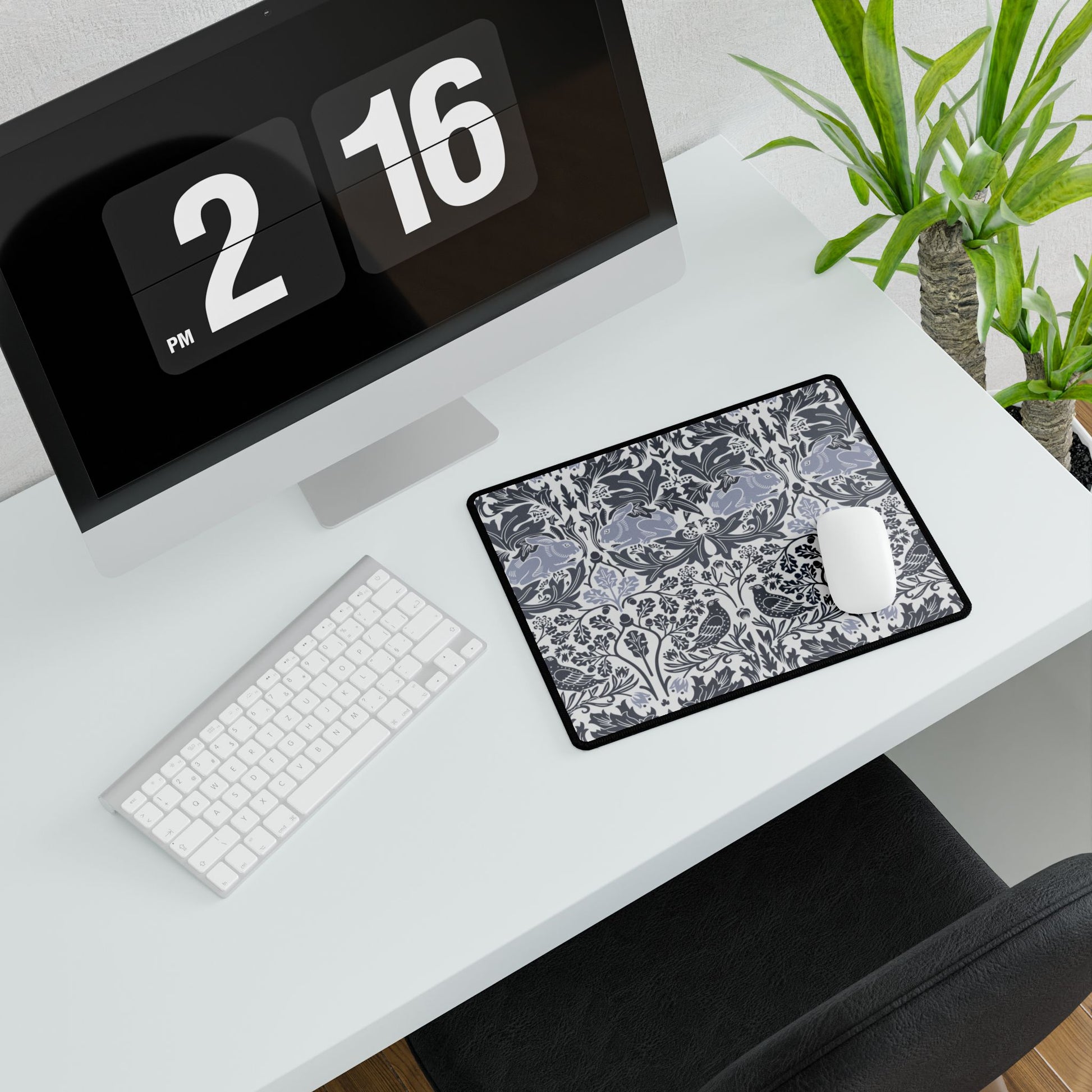 Modern office desk setup with computer, keyboard, mouse, and decorative plant.