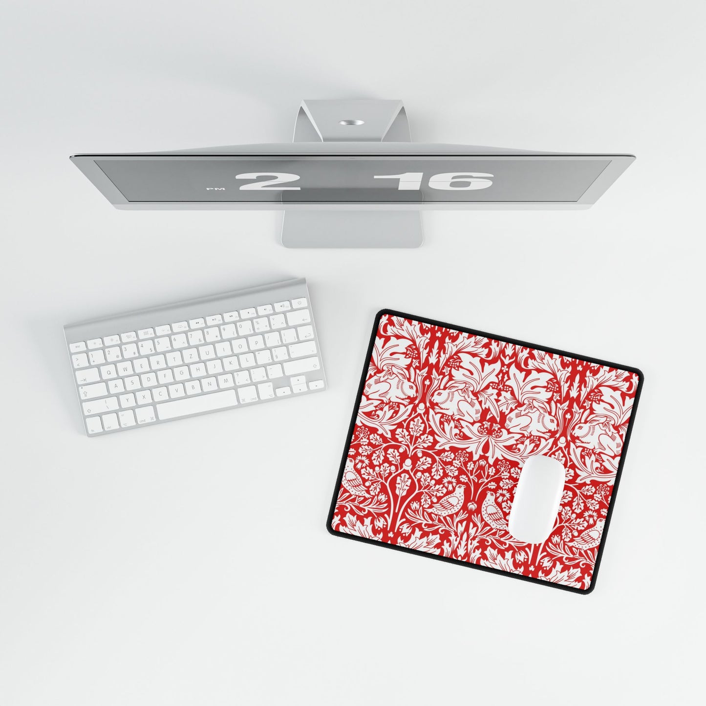 Red and white floral mouse pad on a desk with a computer setup.