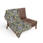 Floral-patterned blanket draped over a brown chair on a white background