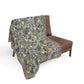 Floral patterned throw blanket draped over a brown chair on a white background