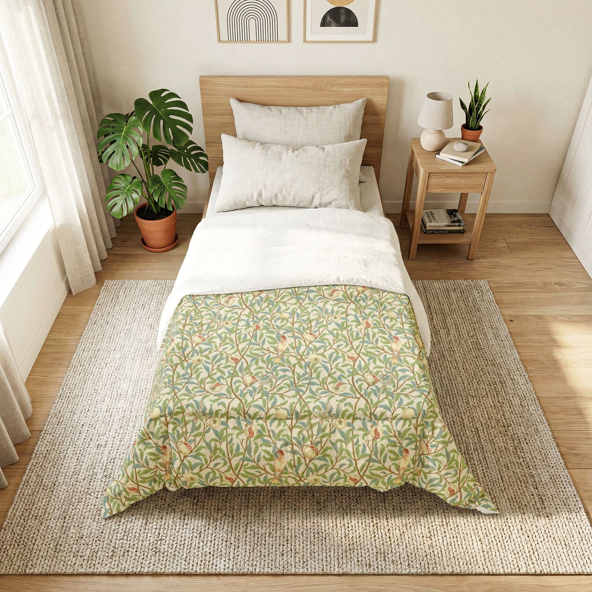 Bedroom with a bed featuring a green floral comforter, side table with lamp and books, and plants.