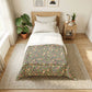 Bedroom with a floral comforter on a bed, side table with books and lamp, and plants.