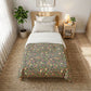 Bedroom with floral-patterned comforter on a bed, nightstand, and plant.
