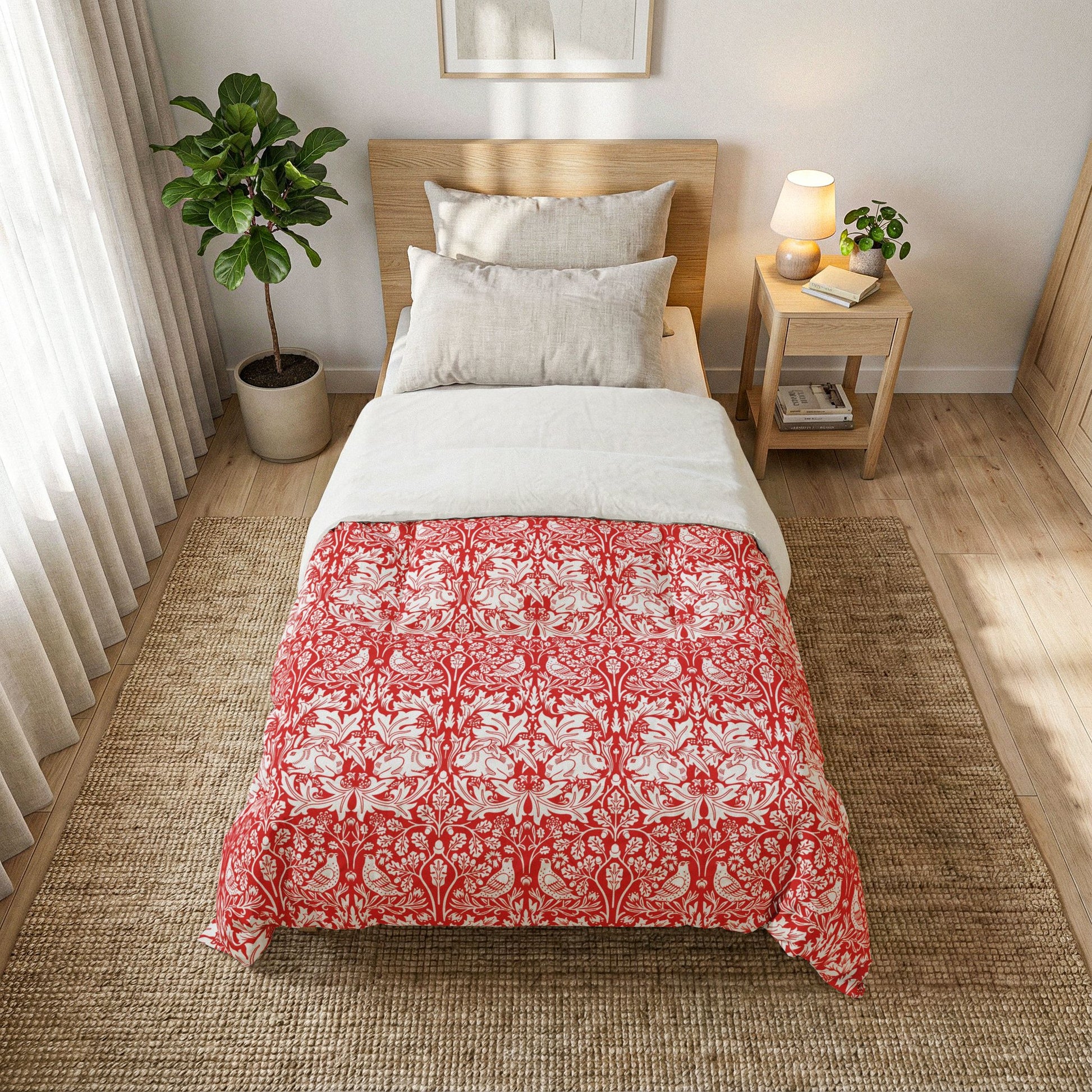 Bedroom with a bed covered in a red and white patterned comforter, nightstand, and plant.