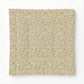 A square fabric or paper napkin featuring a dense, vintage-style floral and botanical pattern in muted yellow, pink, green, and beige tones, displayed flat against a clean white background.