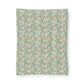 A rectangular fabric or wallpaper sample featuring a dense vintage floral and botanical pattern in muted teal, sage green, cream, and soft rust tones, shown against a plain white background.