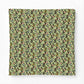 A square fabric item, likely a pillow cover or throw blanket, featuring a dense vintage botanical pattern with green leaves, pink flowers, and small yellow berries on a dark background, shown flat against a light gray backdrop.
