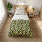 A single bed styled in a bright, modern bedroom, featuring a green and black botanical patterned comforter with orange and blue floral accents, white sheets, and a light wood headboard.