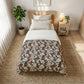 Bedroom with floral-patterned comforter on a bed, nightstand, and plant.