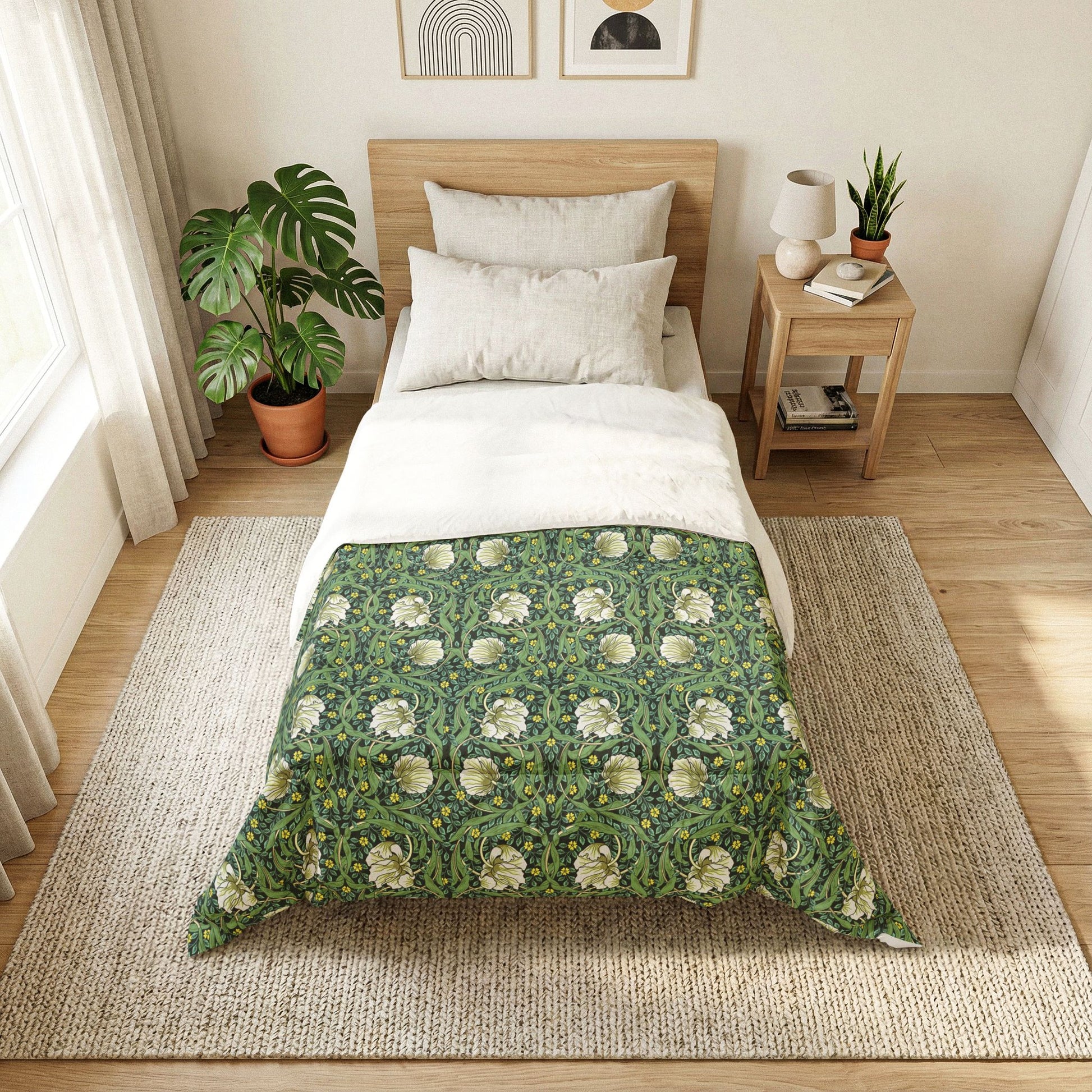 Bedroom with a bed featuring a green floral duvet cover, nightstand with lamp and books, and plants.