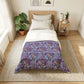 Bedroom with a bed featuring a purple floral patterned comforter.