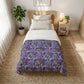 Bedroom with a bed featuring a colorful comforter and a nightstand with a lamp.