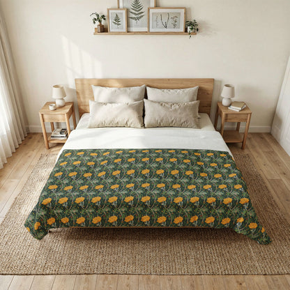 A bed dressed in a green botanical-patterned throw blanket with yellow-orange flowers, styled in a bright, minimalist bedroom with a wooden headboard, bedside tables, and a woven rug.