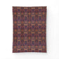 A rectangular textile or rug with an intricate repeating ornamental pattern in deep purple, burgundy, rust orange, and brown tones, shown flat against a plain white background.