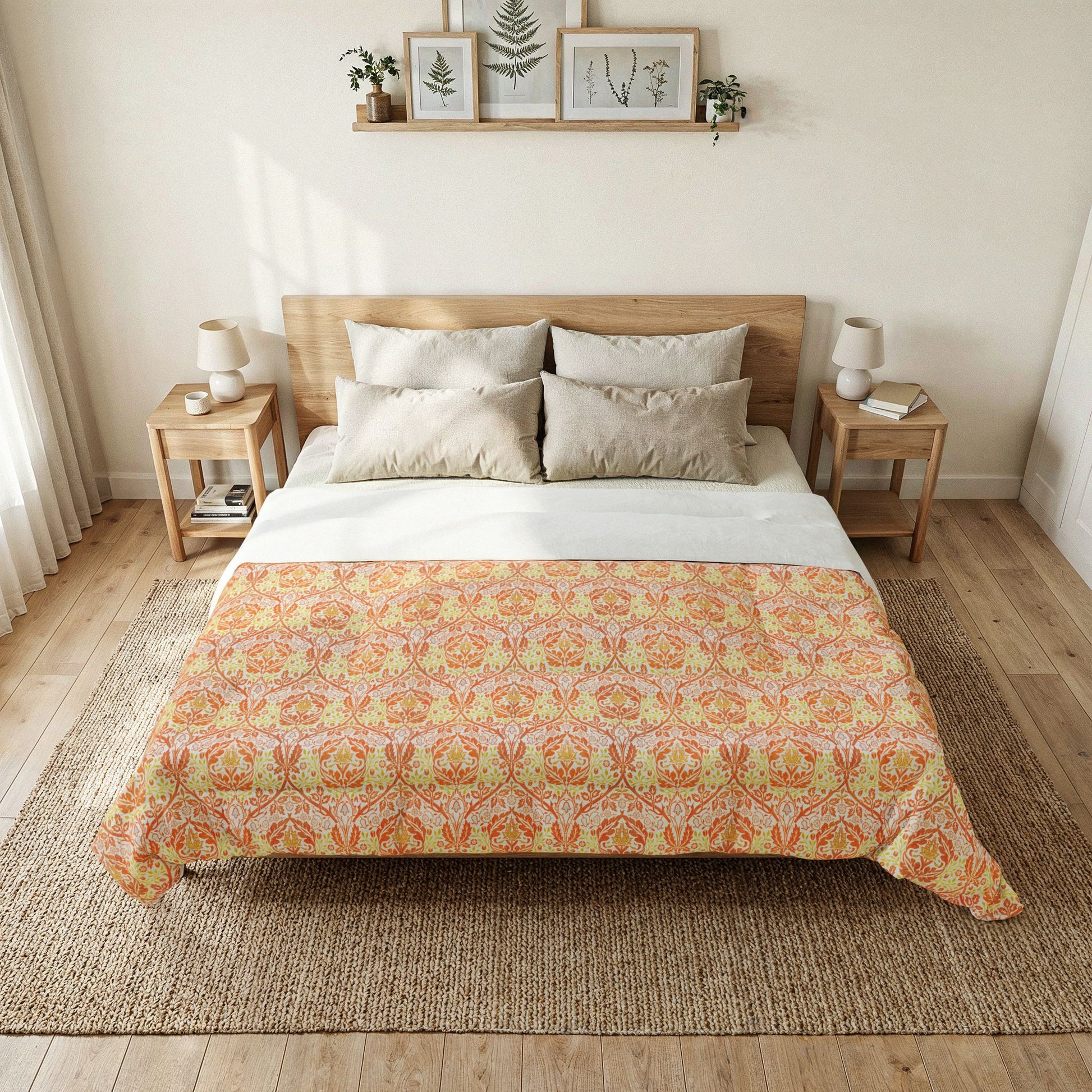 A neatly made bed in a bright bedroom, featuring a patterned comforter in orange, yellow, and beige tones over white sheets, with matching pillows, wooden side tables, lamps, and framed wall art above.