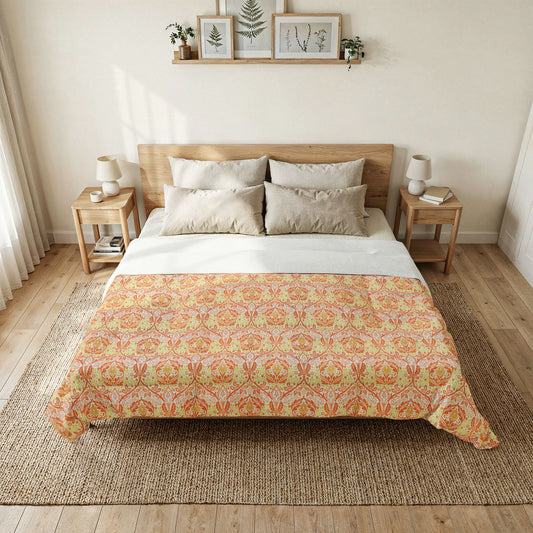 A neatly made bed in a bright bedroom, featuring a patterned comforter in orange, yellow, and beige tones over white sheets, with matching pillows, wooden side tables, lamps, and framed wall art above.